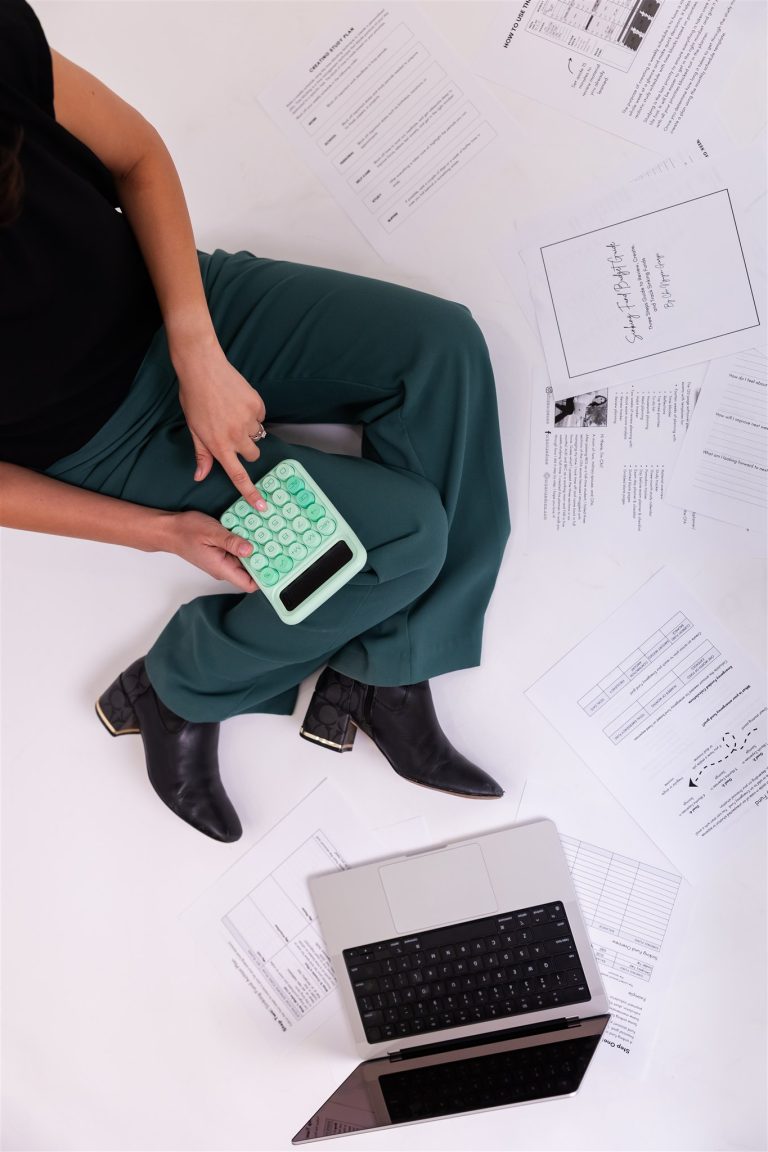Organized CPA working with calculator and laptop in studio for accounting and finance branding